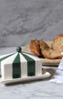 Issy Granger Circus Striped Butter dish with green and white stripes on a marble surface with bread and a knife